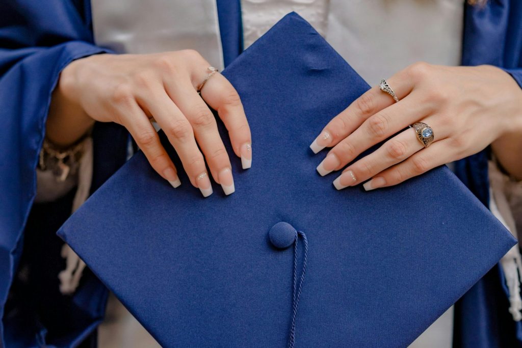 A close-up shot of a graduate holding a navy graduation cap, showcasing achievement.