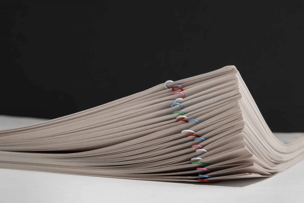 Individual documents clipped together with colored paperclips in a stack