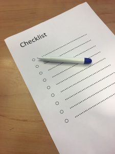 White paper with a blank bulleted checklist and a pen sitting on top of it