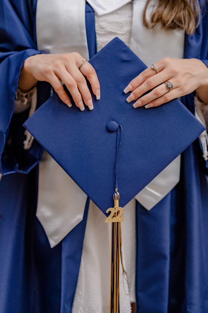 A close-up shot of a graduate holding a navy graduation cap, showcasing achievement.