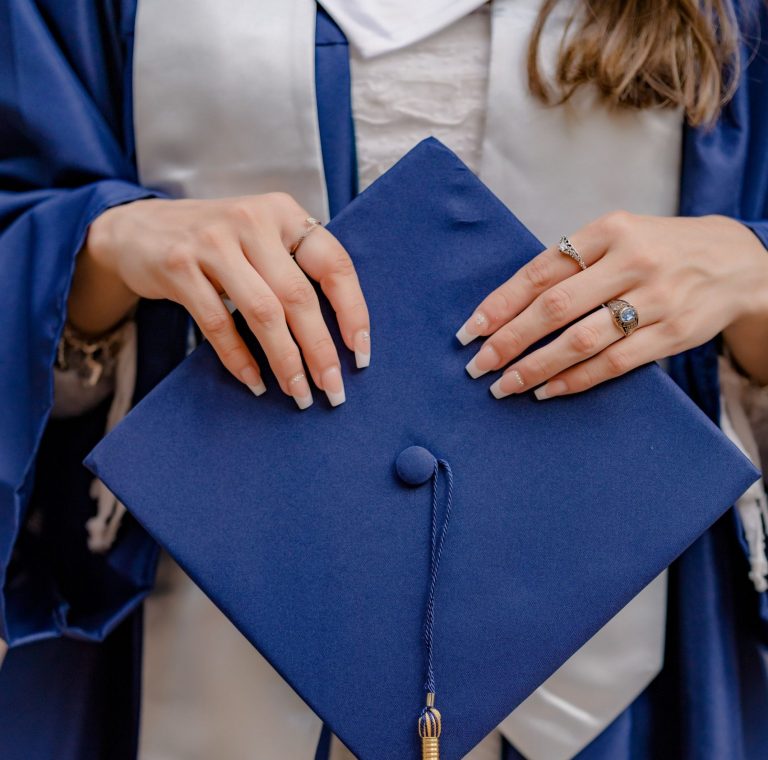 A close-up shot of a graduate holding a navy graduation cap, showcasing achievement.